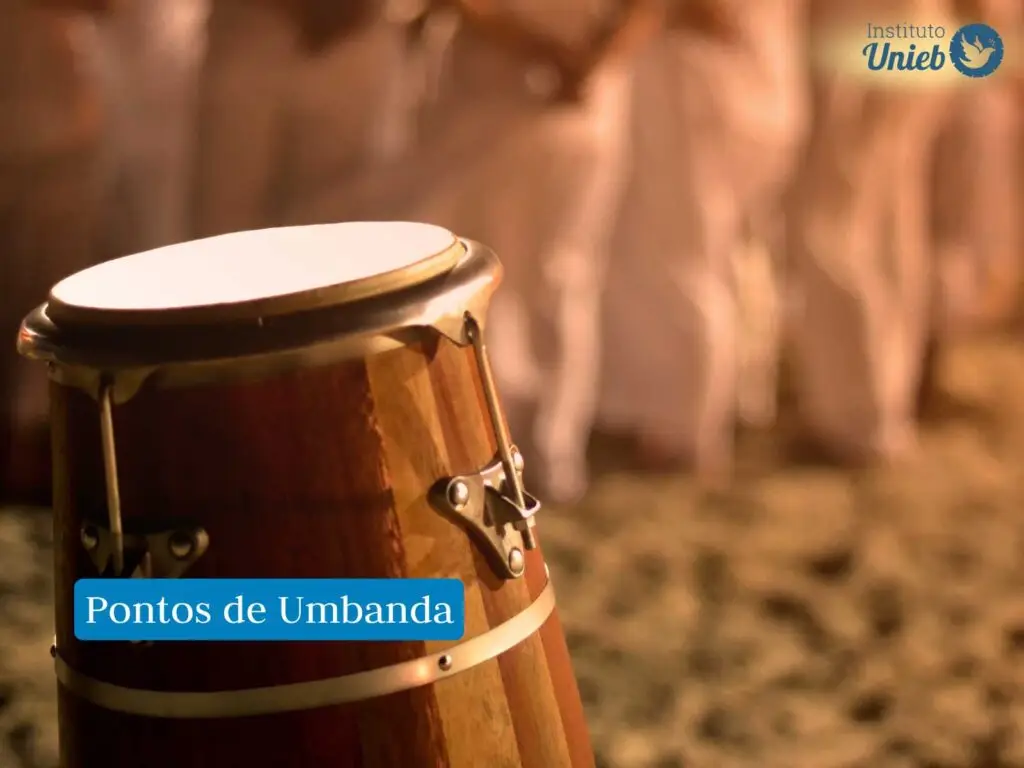 tambor, instrumento usado no culto da Umbanda, ao fundo há pessoas vestidas de branco em culto, com frase em fundo azul que diz "Pontos de Umbanda" e logo acima do Instituto Unieb