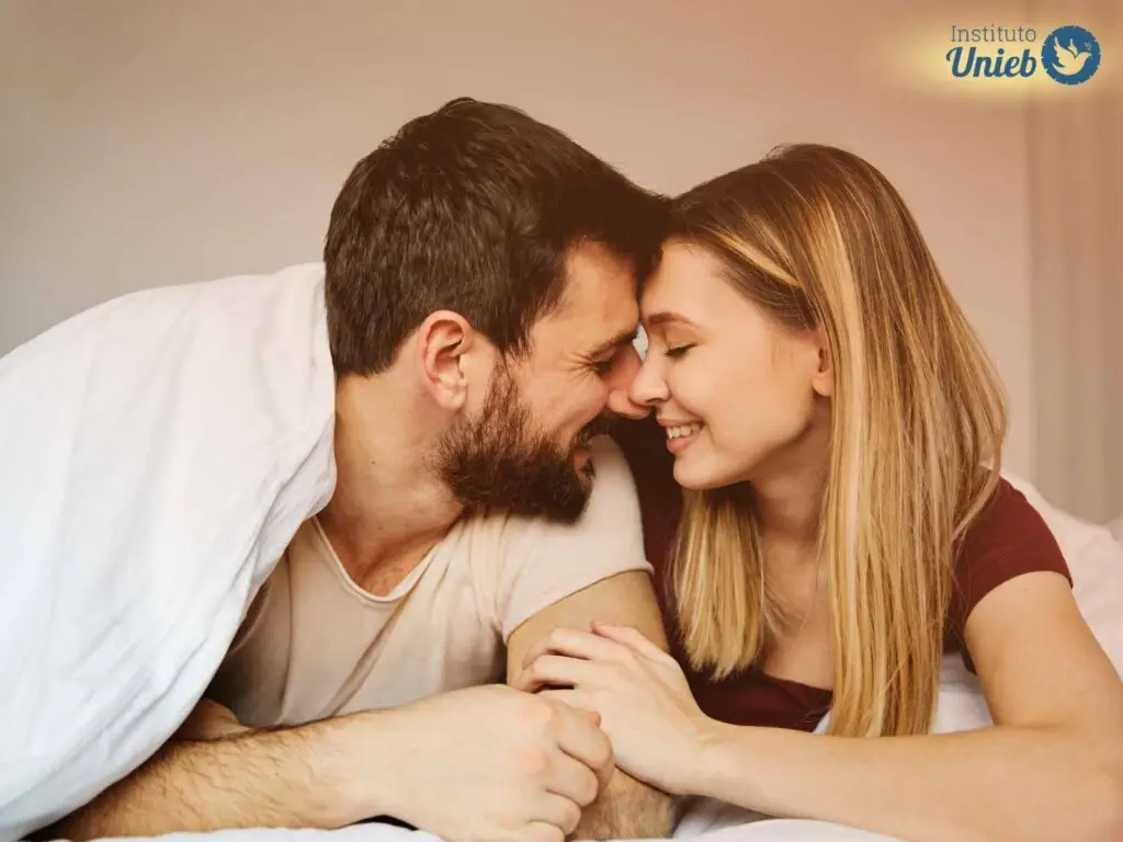 homem e mulher embaixo de cobertor branco se olhando em momento de intimidade