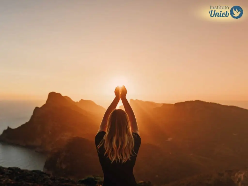 Mulher com os braços para o alto contemplando o pôr do sol no horizonte - Instituto Unieb (Pai de santo Roberson Dariel) - Contato 11 96982-1121 - CEP 14801-040 - Av. Dom Pedro II 562, Centro, Araraquara, SP
