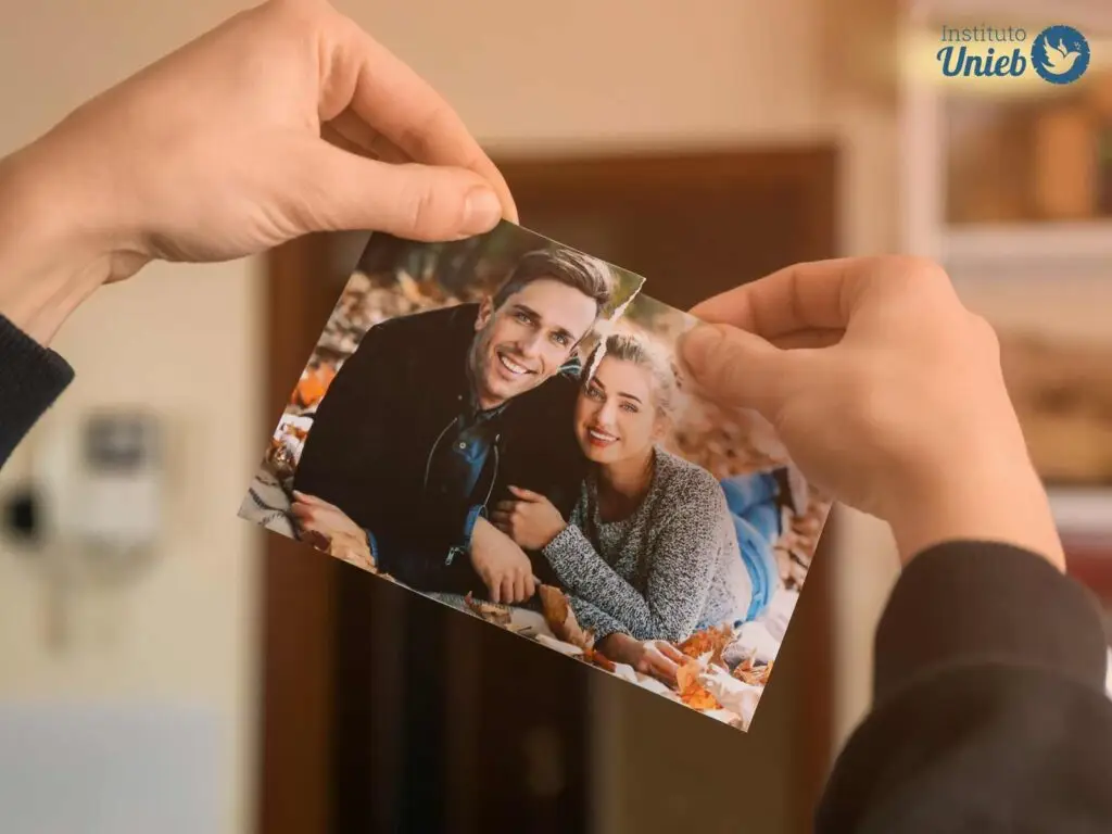 Mãos de uma pessoa rasgando uma fotografia de um casal ao meio
