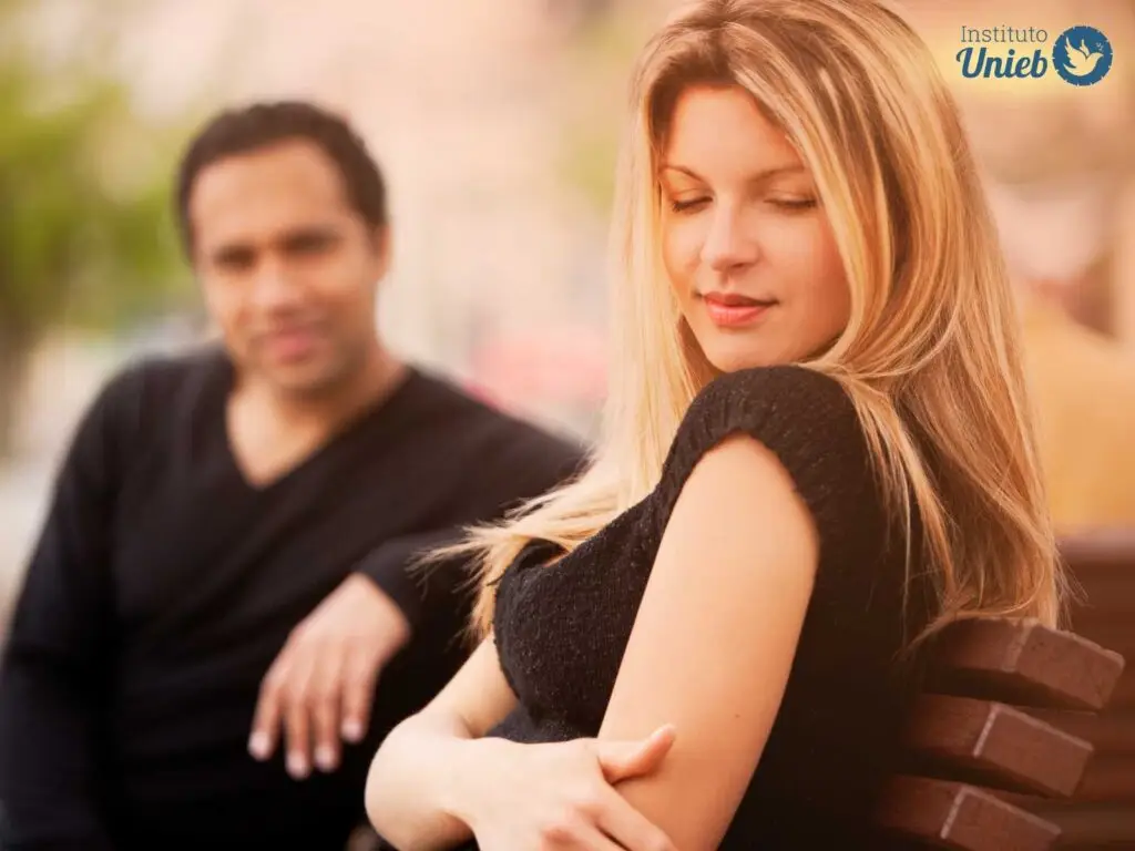 Homem olhando para mulher que segura os braços em torno do corpo demonstrando timidez