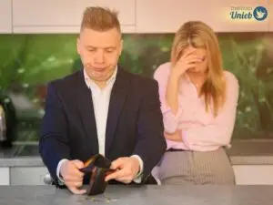 Homem contanto moedas com a carteira aberta e mulher ao fundo com a mão na cabeça