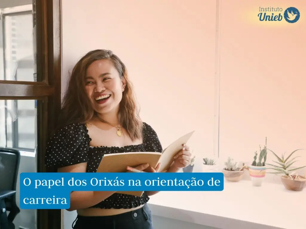 Mulher sorrindo usando vestido preto com caderno aberto nas mãos
