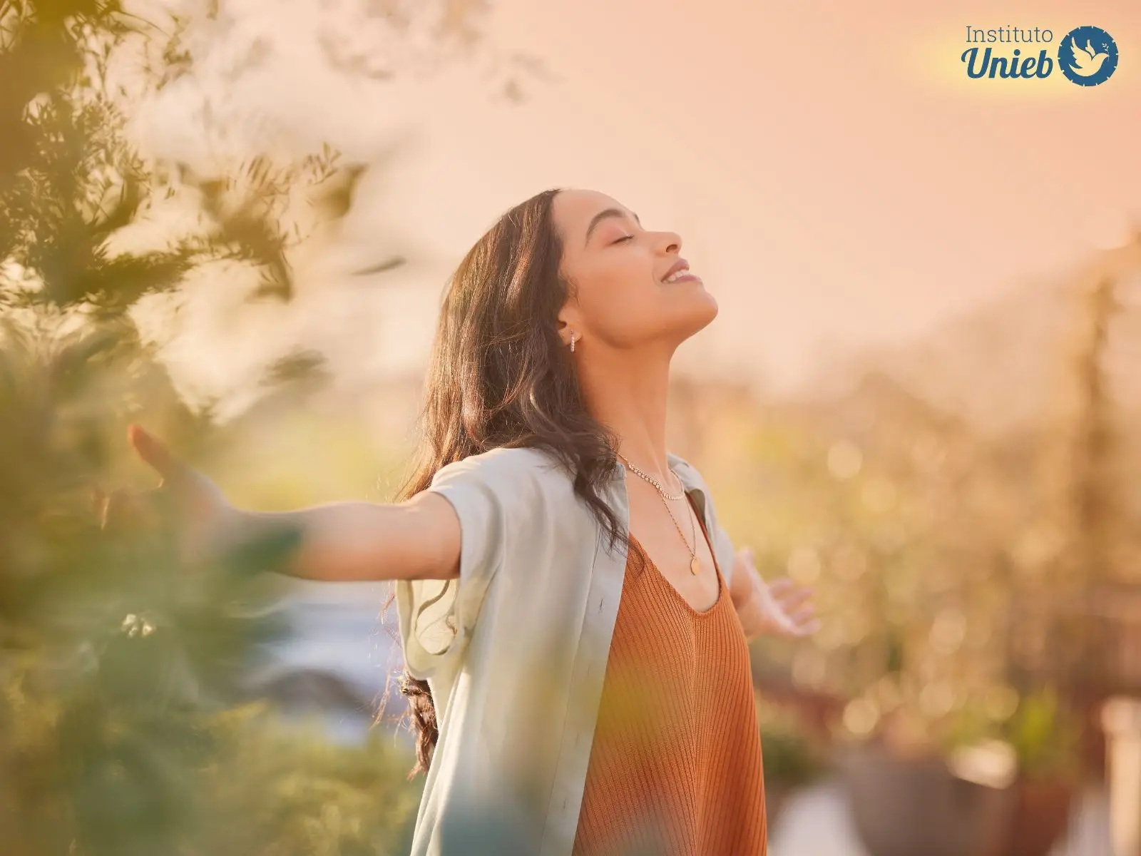 Mulher com os braços abertos e cabeça para cima de olhos fechados em meio a natureza - Instituto Unieb (Pai de santo Roberson Dariel) - Contato 11 96982-1121 - CEP 14801-040 - Av. Dom Pedro II 562, Centro, Araraquara, SP