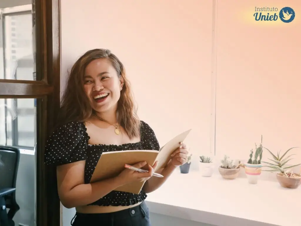 Mulher sorrindo usando vestido preto com caderno aberto nas mãos - Instituto Unieb (Pai de santo Roberson Dariel) - Contato 11 96982-1121 - CEP 14801-040 - Av. Dom Pedro II 562, Centro, Araraquara, SP