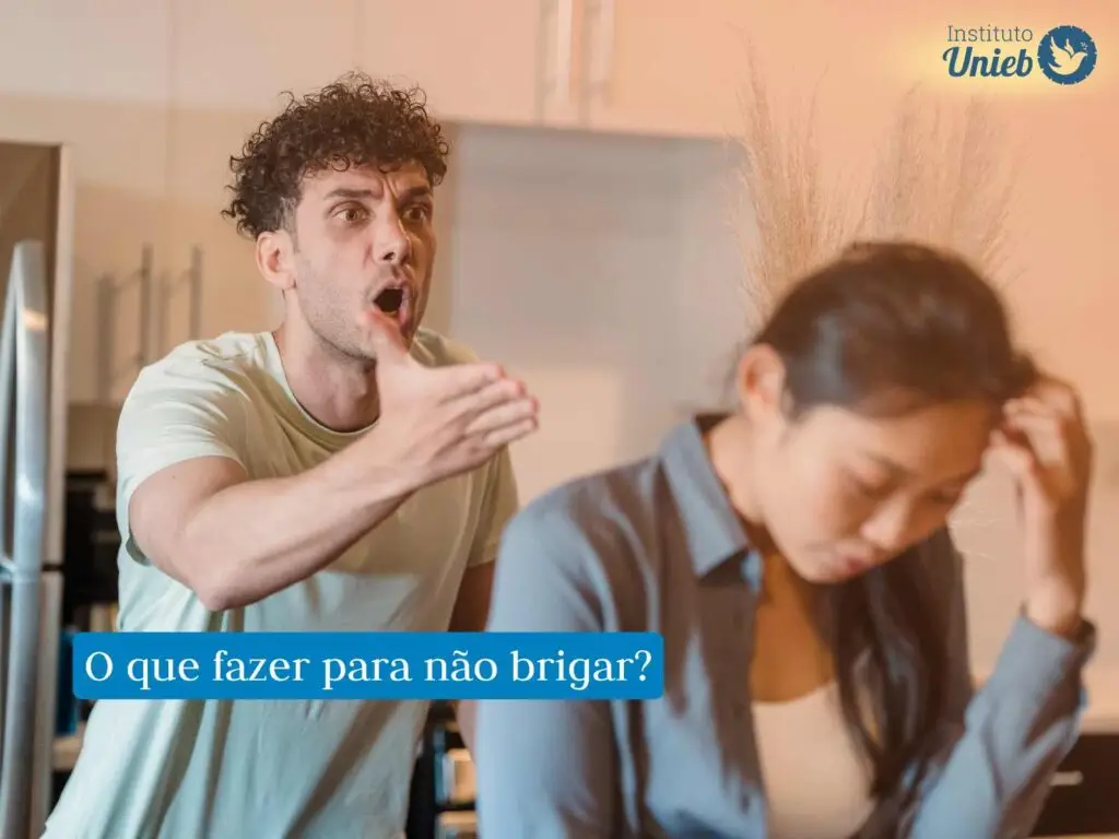 Mulher com cabeça baixa de costas para homem com braço esticado diante de uma briga