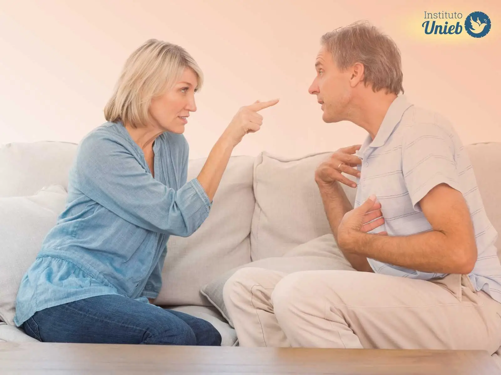 Homem e mulher de frente para o outro sentados em um sofá discutindo a relação