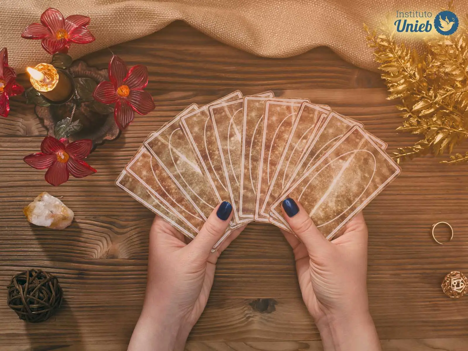Mãos femininas seguram um baralho de cartas de tarot aberto em cima de mesa de atendimento espiritual