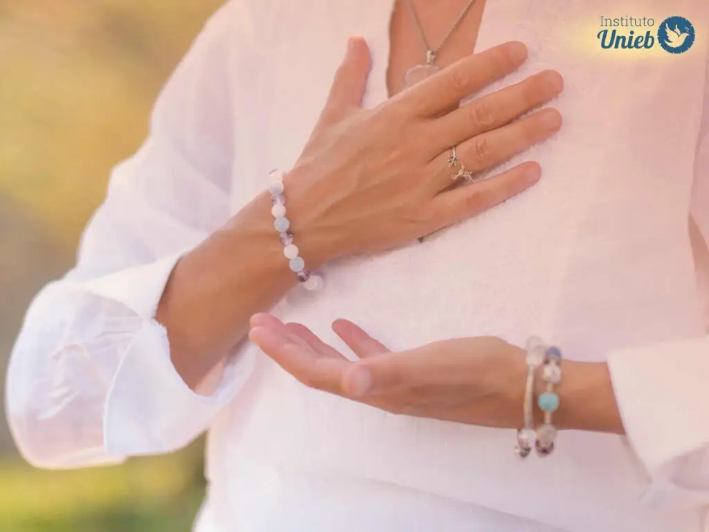 Pessoa vestindo branco com uma mão aberta e outra no coração