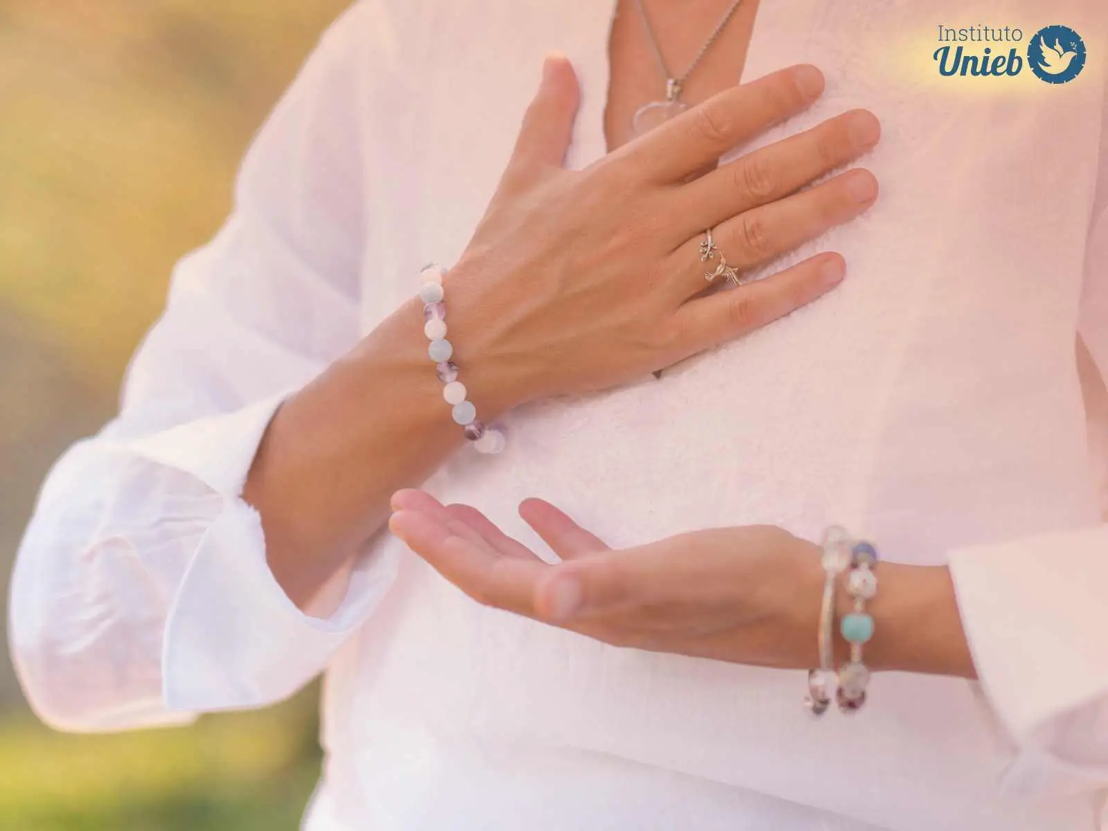 Pessoa vestindo branco com uma mão aberta e outra no coração