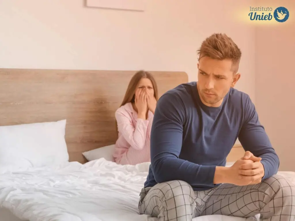 Homem e mulher sentados na cama com expressão de mágoa