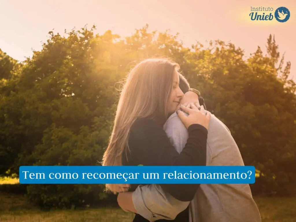 Casal de homem e mulher se abraçando com raios de sol brilhando no horizonte