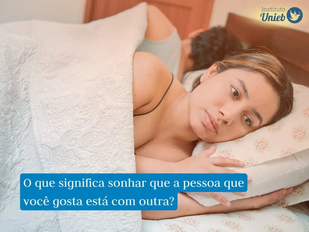 Casal deitado na cama de costas um para o outro, a mulher está com uma expressão deprimida