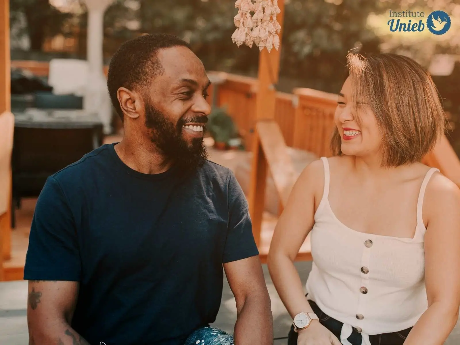 Homem e mulher sentados olhando e sorrindo um para o outro