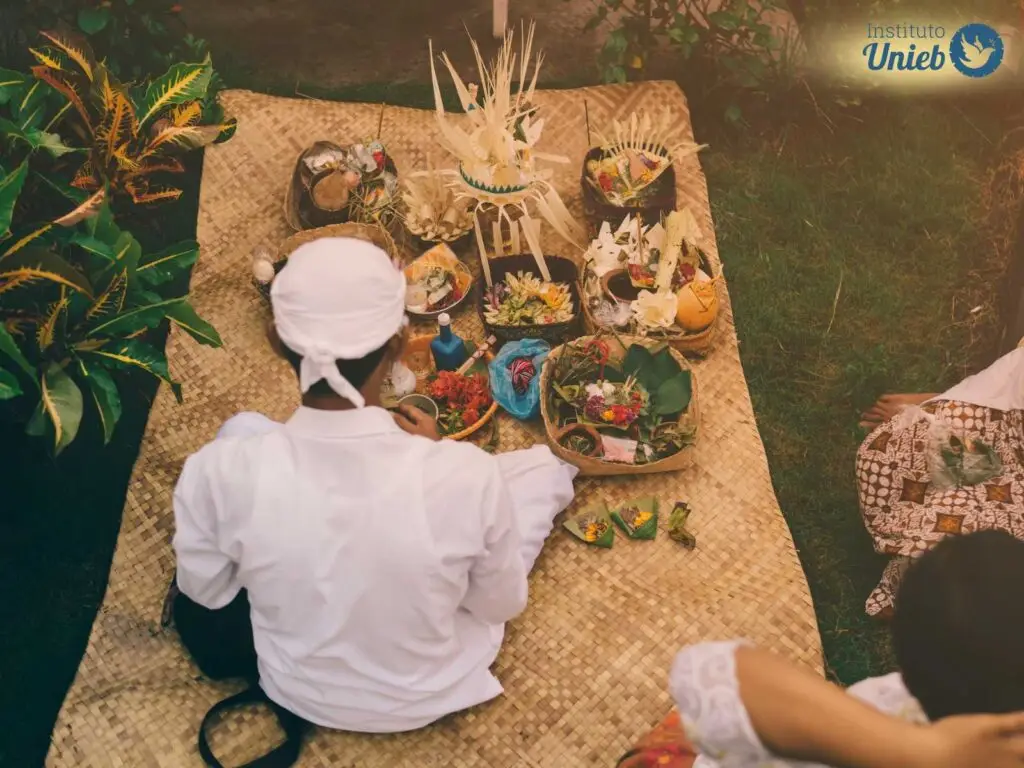 Homem com vestes brancas da religião afro-brasileira Umbanda em cima de tapete de palha preparando uma oferenda religiosa - Instituto Unieb (Pai de santo Roberson Dariel) - Contato 11 96982-1121 - CEP 14801-040 - Av. Dom Pedro II 562, Centro, Araraquara, SP