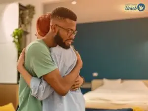 Homem e mulher se abraçando em pé dentro de um quarto