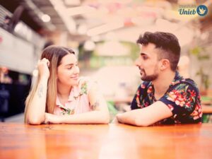 Homem e mulher sentados de frente um para o outro conversando em local aberto