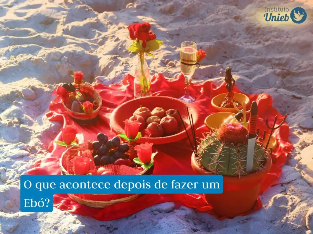 Oferenda preparada para Entidades Espirituais em vasilha vermelha, com maças, rosas vermelhas, taças e outros elementos na cor vermelho, colocada na areia da praia