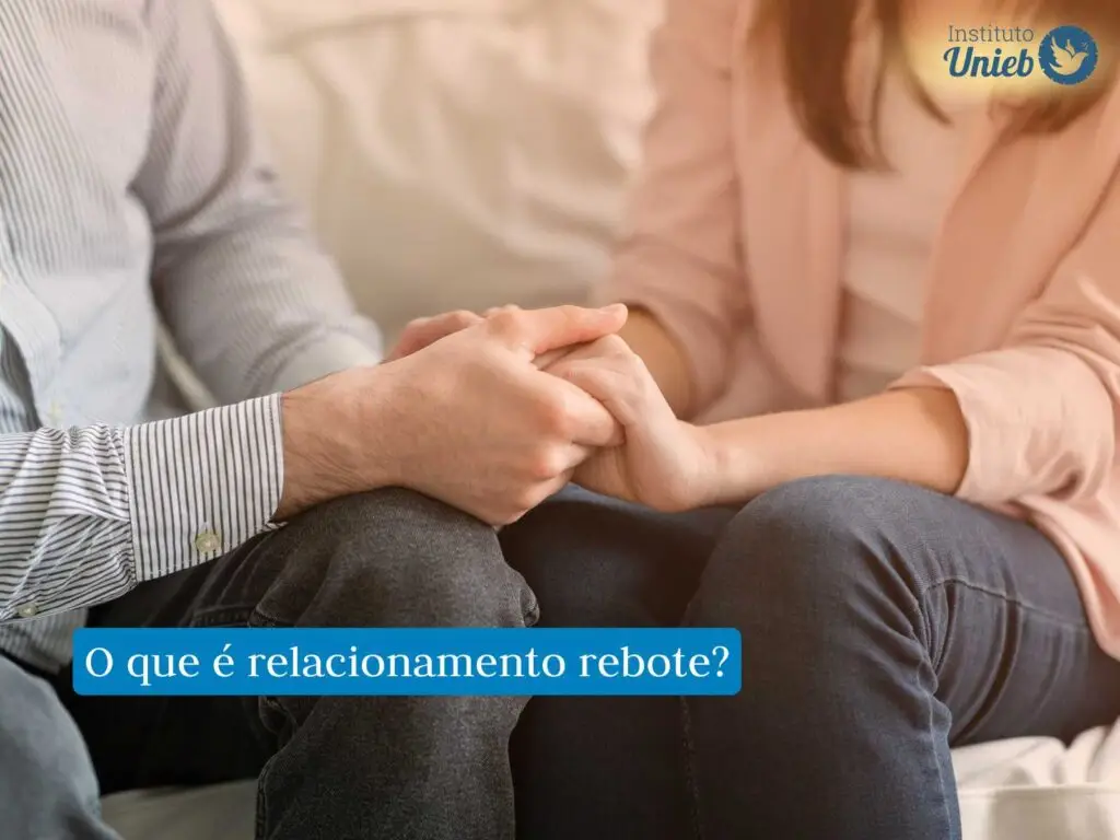 Casal sentado de frente para o outro com joelhos encostando um no outro e segurando as mãos