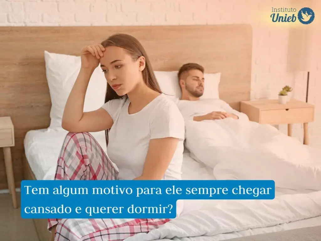 Homem deitado na cama embaixo das cobertas e mulher sentada ao pé da cama com cabeça apoiada na mão direita e joelho