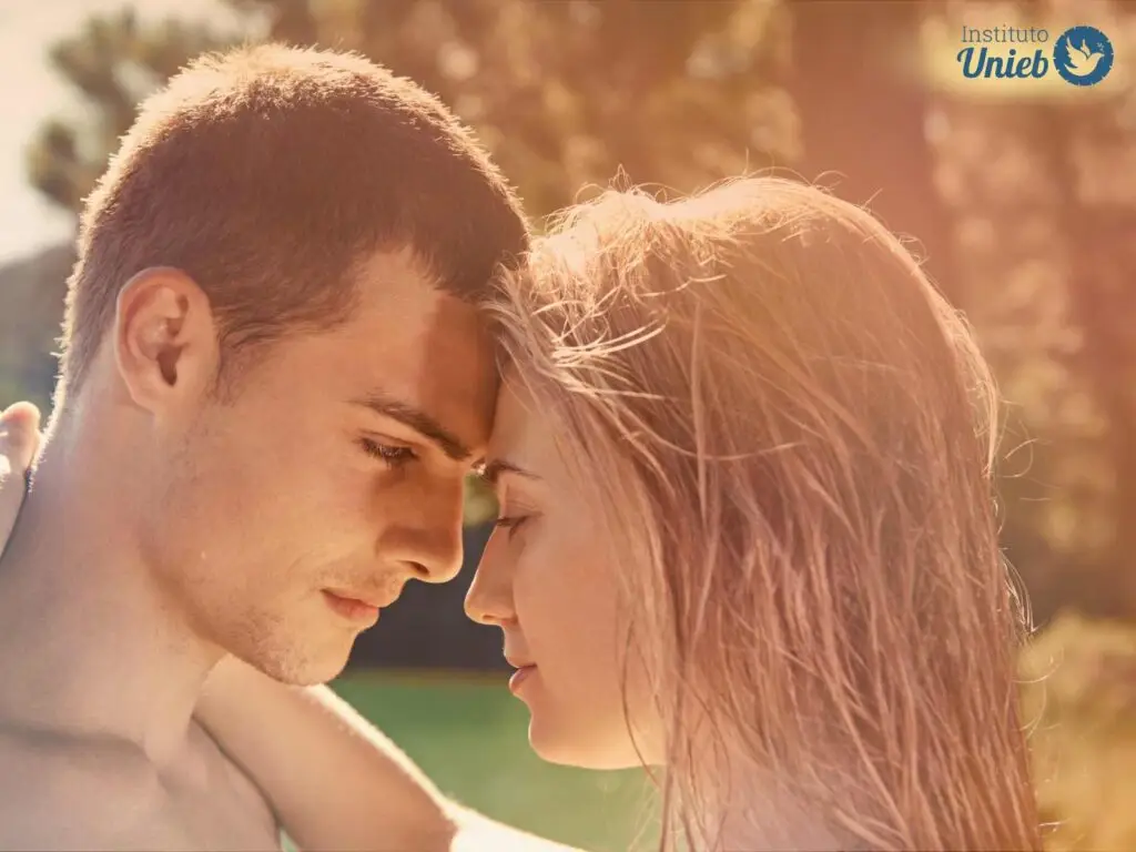 Casal de homem e mulher se olhando e se abraçando ao ar livre