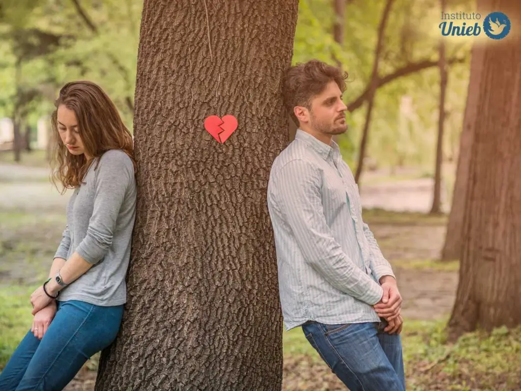 Homem e mulher em pé encostados um de costas para o outro em uma árvore com um coração partido ao meio preso nela - Instituto Unieb (Pai de santo Roberson Dariel) - Contato 11 96982-1121 - CEP 14801-040 - Av. Dom Pedro II 562, Centro, Araraquara, SP