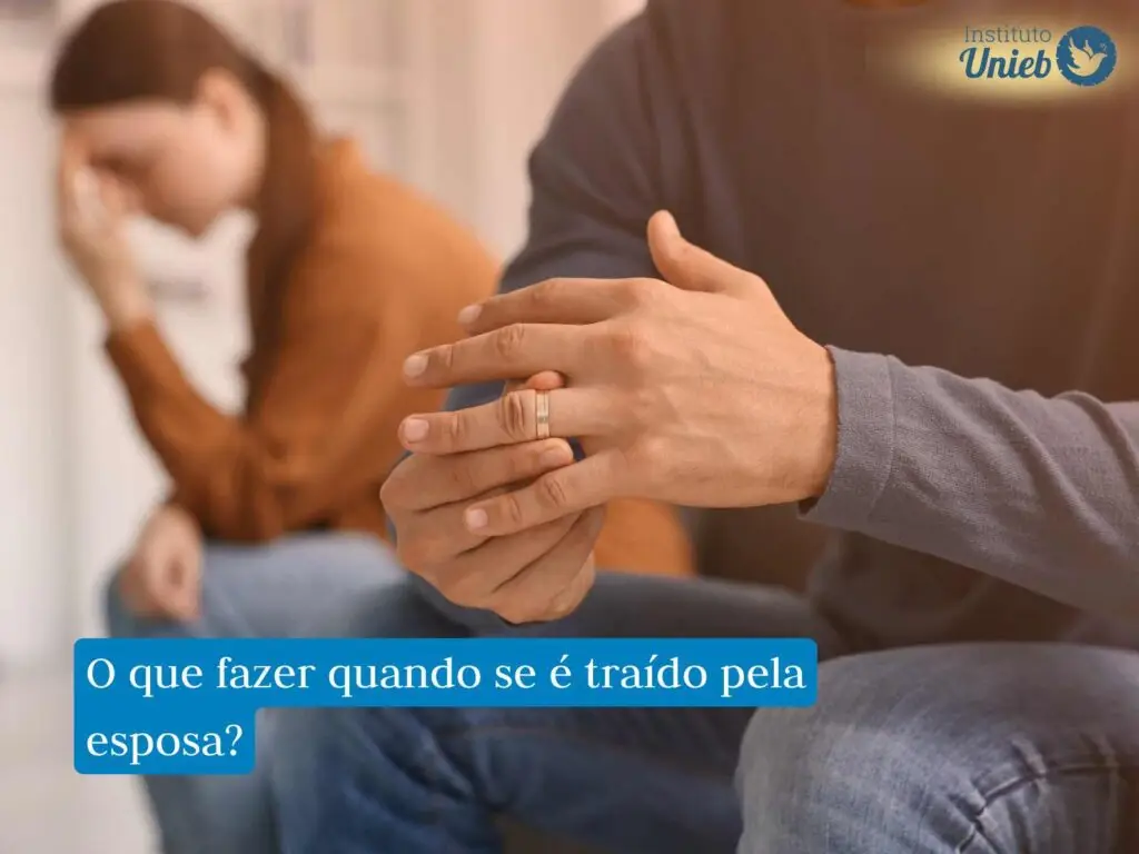 Homem sentado retirando aliança de casamento do dedo e mulher ao fundo desfocada com a mão na cabeça