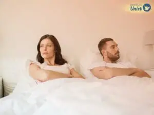 Casal deixado na cama de braços cruzados e expressão de frustração