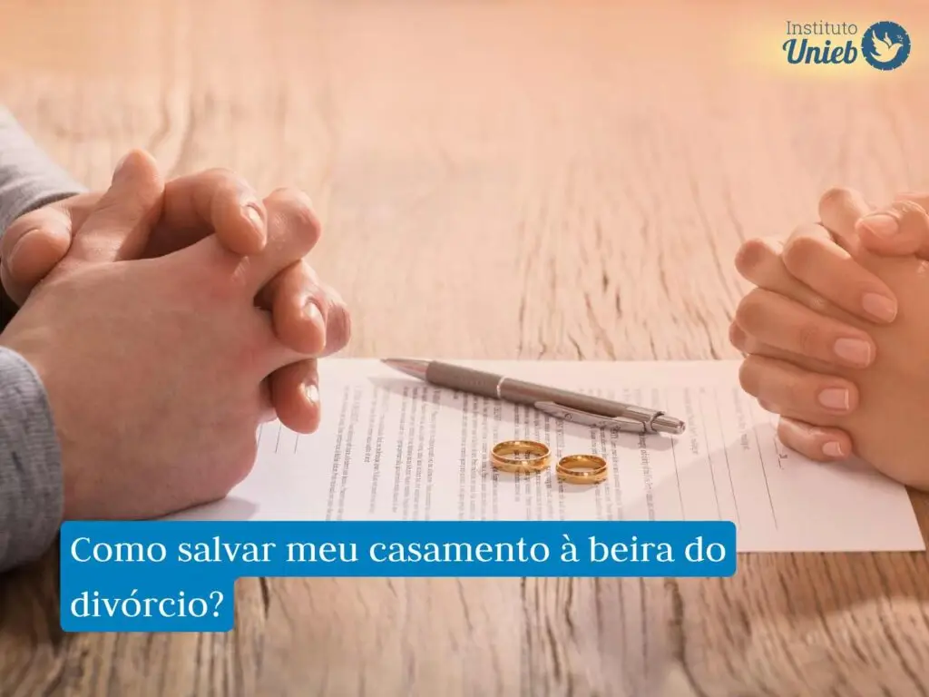 Homem e mulher com mãos fechadas em cima de uma mesa de madeira com papel de divórcio, alianças e caneta em cima