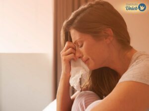 Mulher chorando segurando um lenço nas mãos e secando o rosto