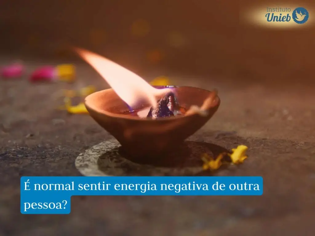 Vela queimando em porta-velas no chão com algumas flores caídas