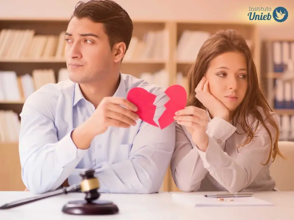 Homem e mulher sentados um ao lado do outro segurando um coração partido ao meio