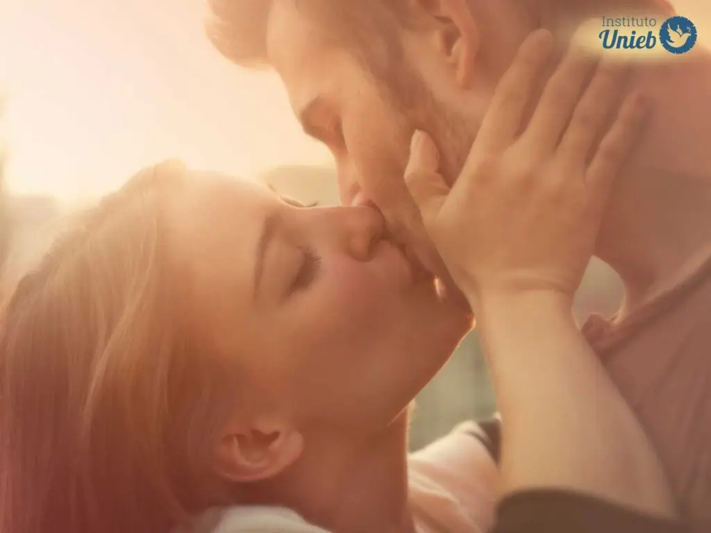 Homem e mulher se beijando ao ar livre com luz do sol ao fundo