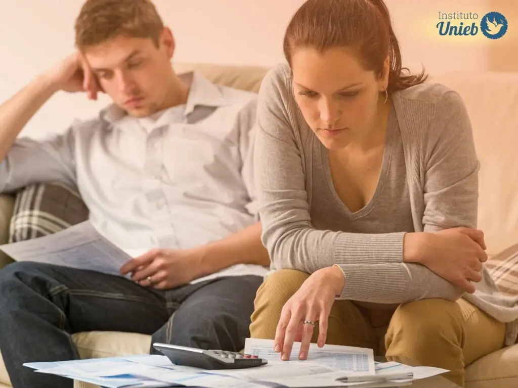 Casal sentado no sofá olhando para boletos e contas