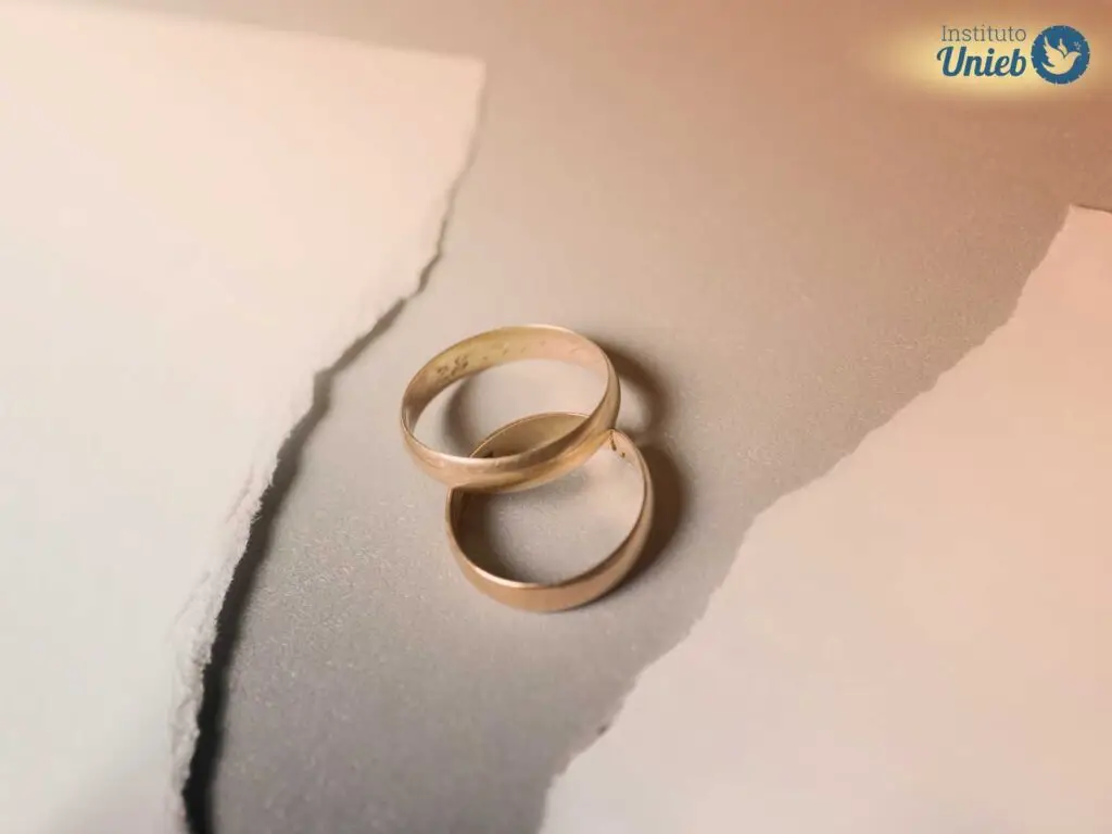 Duas alianças sob uma mesa com um papel branco cortado ao meio