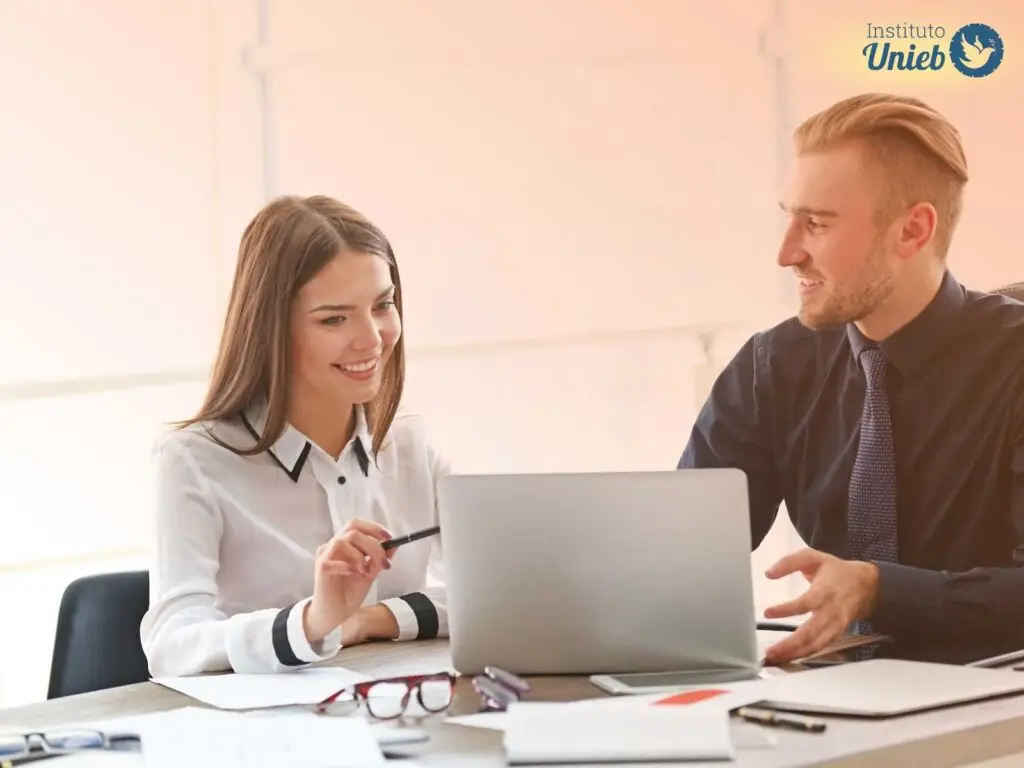 Homem e mulher sentados à mesa de trabalho em um escritório
