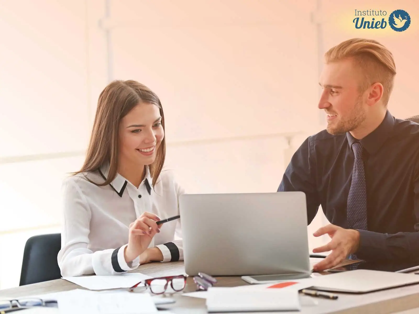 Homem e mulher sentados à mesa de trabalho em um escritório