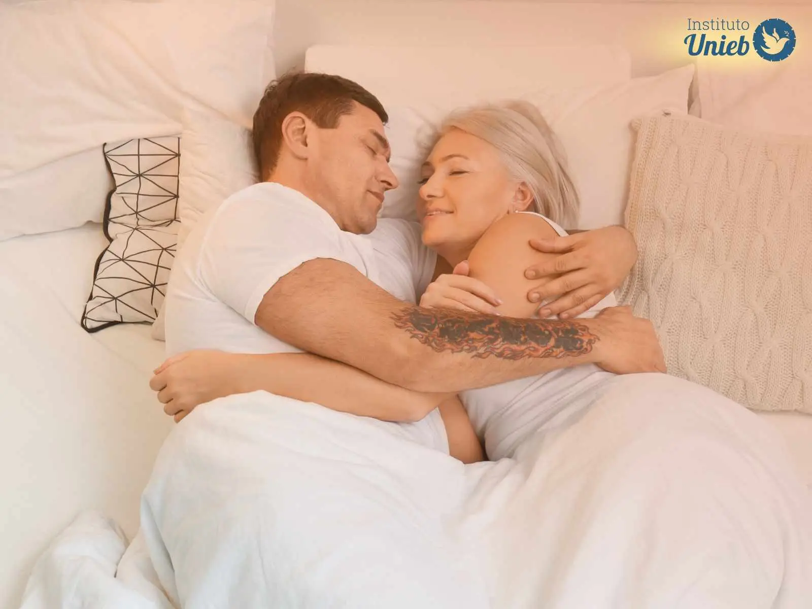 Casal de homem e mulher madura dormindo abraçados na cama