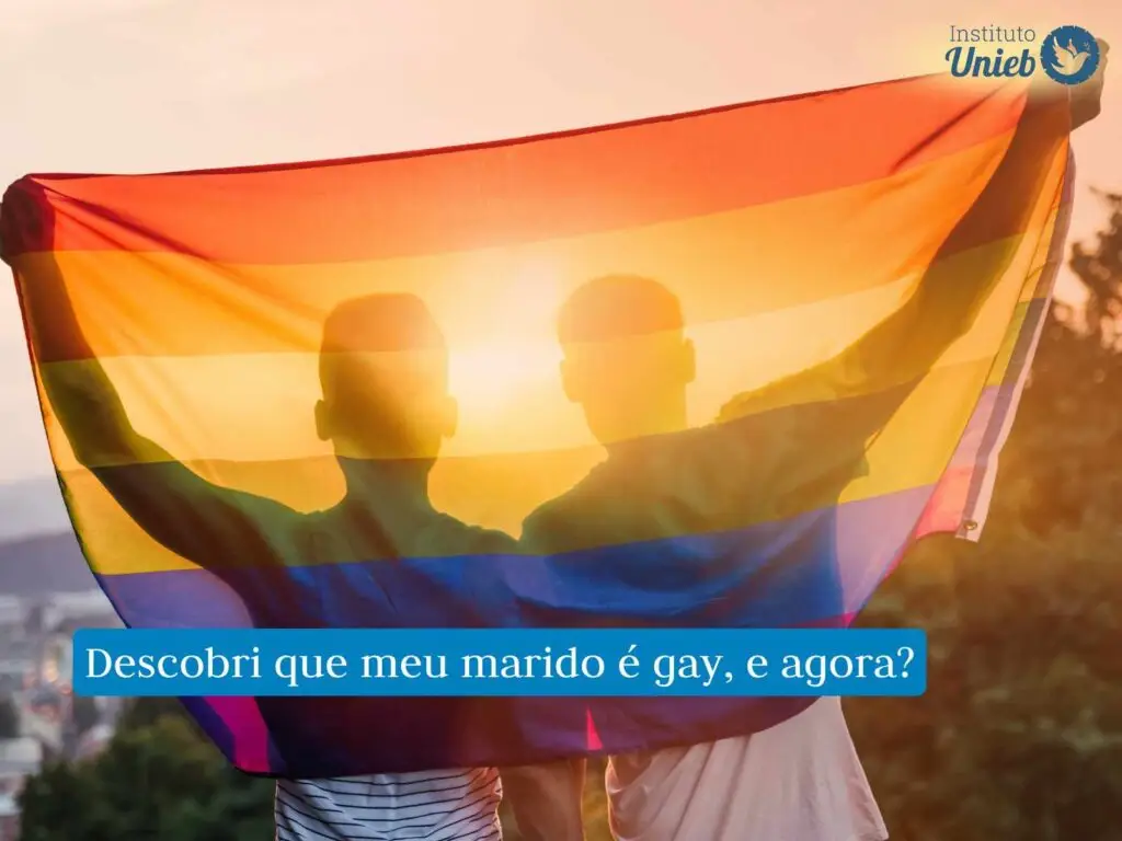 Dois homens abraçados de costas com uma bandeira arco-íris que simboliza a comunidade LGBT