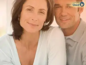 Homem e mulher de meia-idade próximos um do outro olhando para frente com sorriso no rosto