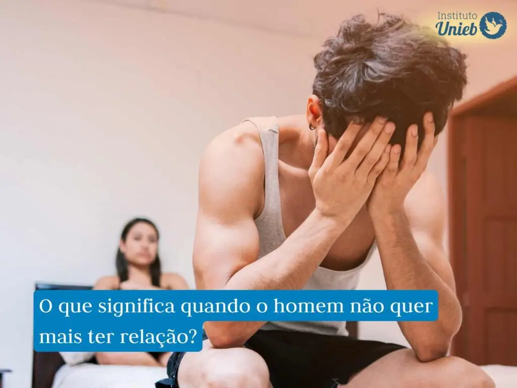 Homem sentado ao pé da cama com as mãos no rosto e cotovelos nos joelhos e mulher ao fundo sentada na cama com expressão de frustração