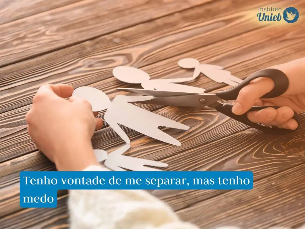 Mãos usando uma tesoura para cortar uma família de papel em cima de uma mesa de madeira