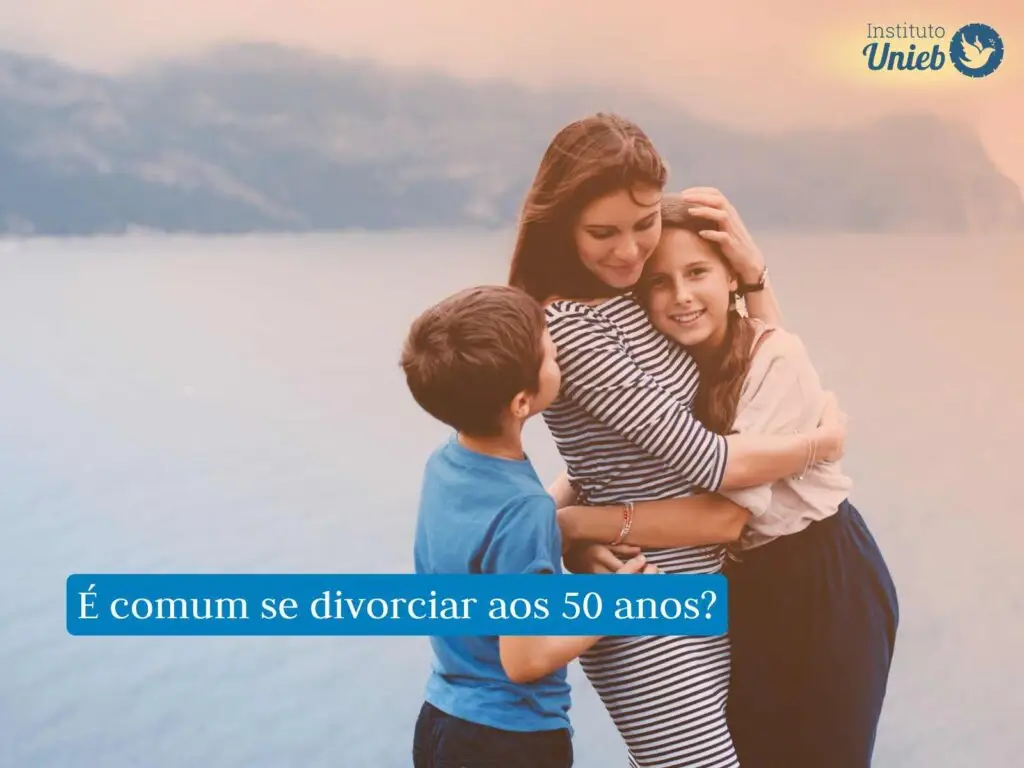 Mulher de vestido listrado abraçando sua filha com filho ao seu lado em momento de carinho
