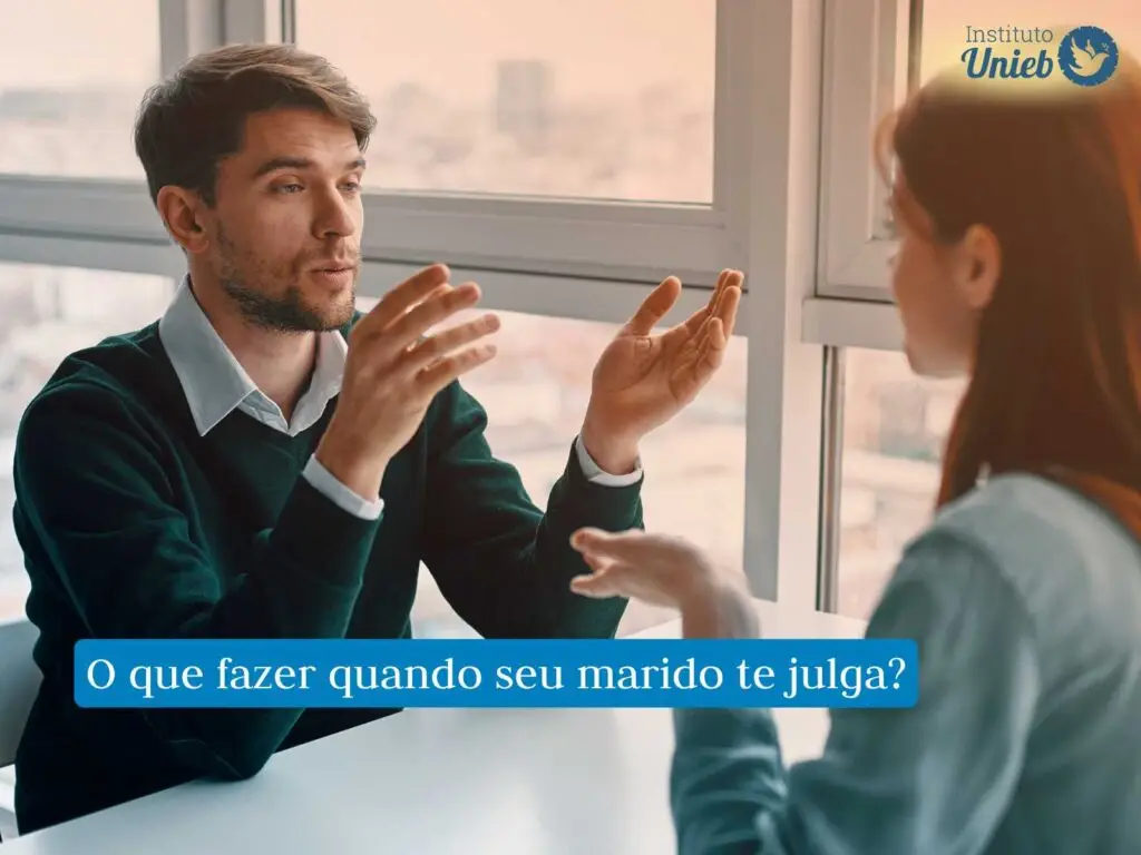 Meu marido me julga muito, o que fazer? Homem e mulher sentados à mesa em meio a uma discussão de casal
