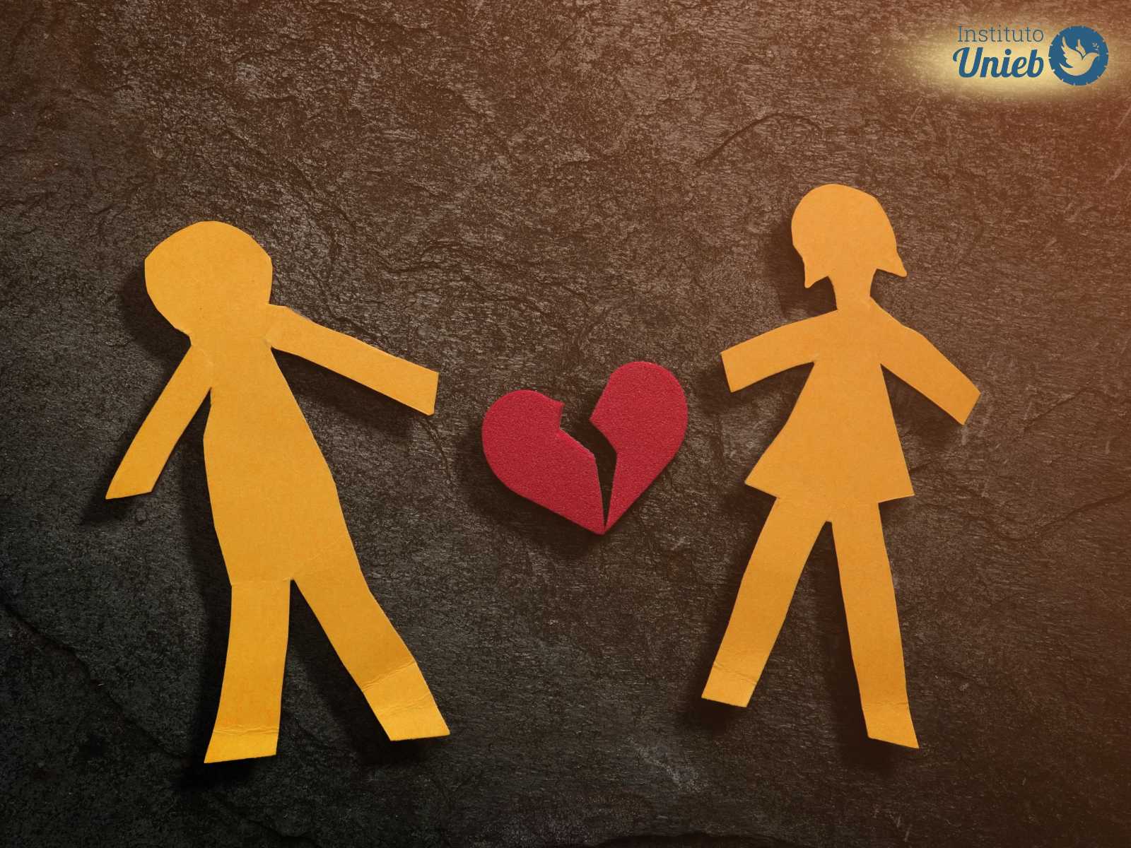 Figuras de homem e mulher de papel com coração também de papel partido ao meio