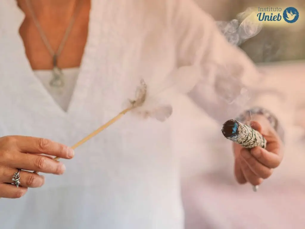 Pessoa usando roupas brancas segurando um defumador de ervas em uma mão e outro acessório de defumação na outra mão - Instituto Unieb (Pai de santo Roberson Dariel) - Contato 11 96982-1121 - CEP 14801-040 - Av. Dom Pedro II 562, Centro, Araraquara, SP