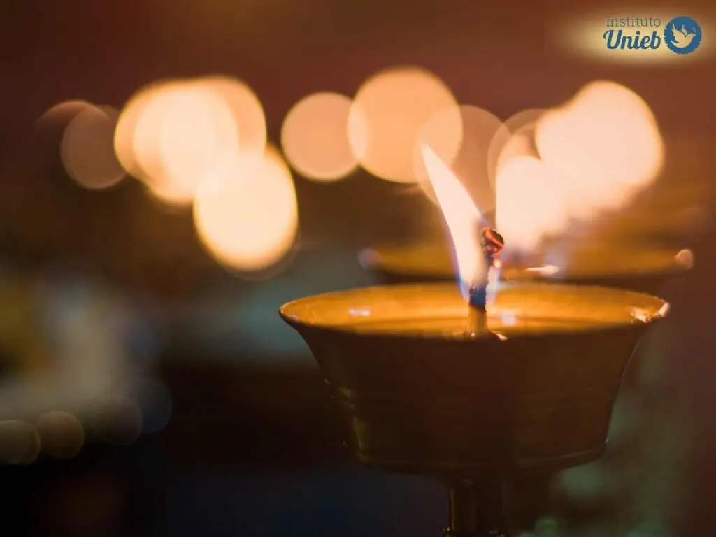 Vela acesa à frente da câmera com fundo escurecido e luzes de outras velas esfumaçadas ao fundo - Instituto Unieb (Pai de santo Roberson Dariel) - Contato 11 96982-1121 - CEP 14801-040 - Av. Dom Pedro II 562, Centro, Araraquara, SP