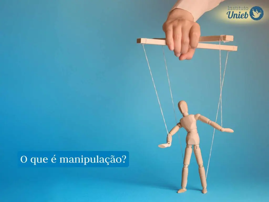 Pequeno boneco de madeira do tipo marionete preso por cordas a uma base de madeira que é segurada por uma mão no alto