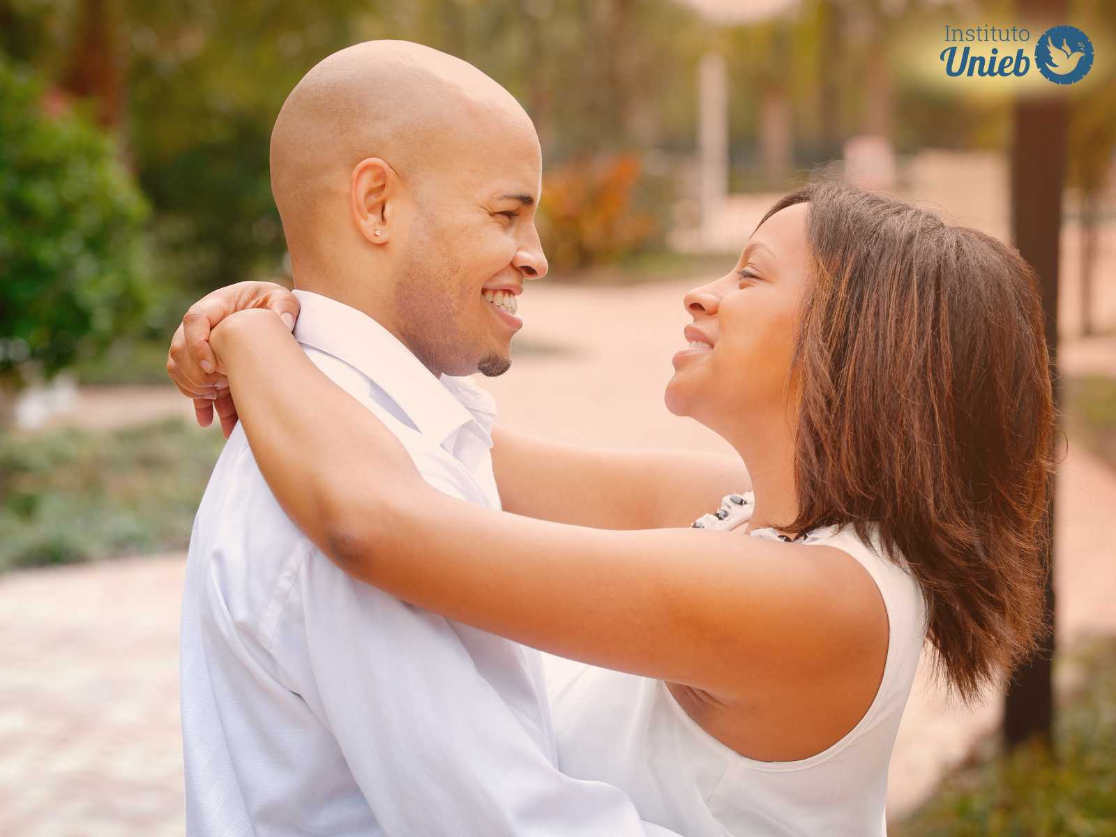 Casal vestindo roupa branca ao ar livre se abraçando