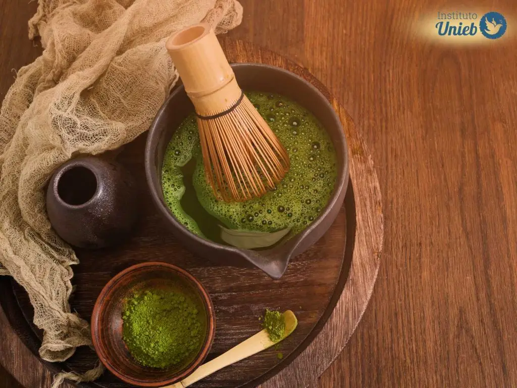 Materiais para a preparação de banho de ervas como um pote com ervas verdes maceradas, outro pote com água com ervas, um tecido próximo aos potes dentro de uma bandeja de madeira em uma mesa de madeira - Instituto Unieb (Pai de santo Roberson Dariel) - Contato 11 96982-1121 - CEP 14801-040 - Av. Dom Pedro II 562, Centro, Araraquara, SP